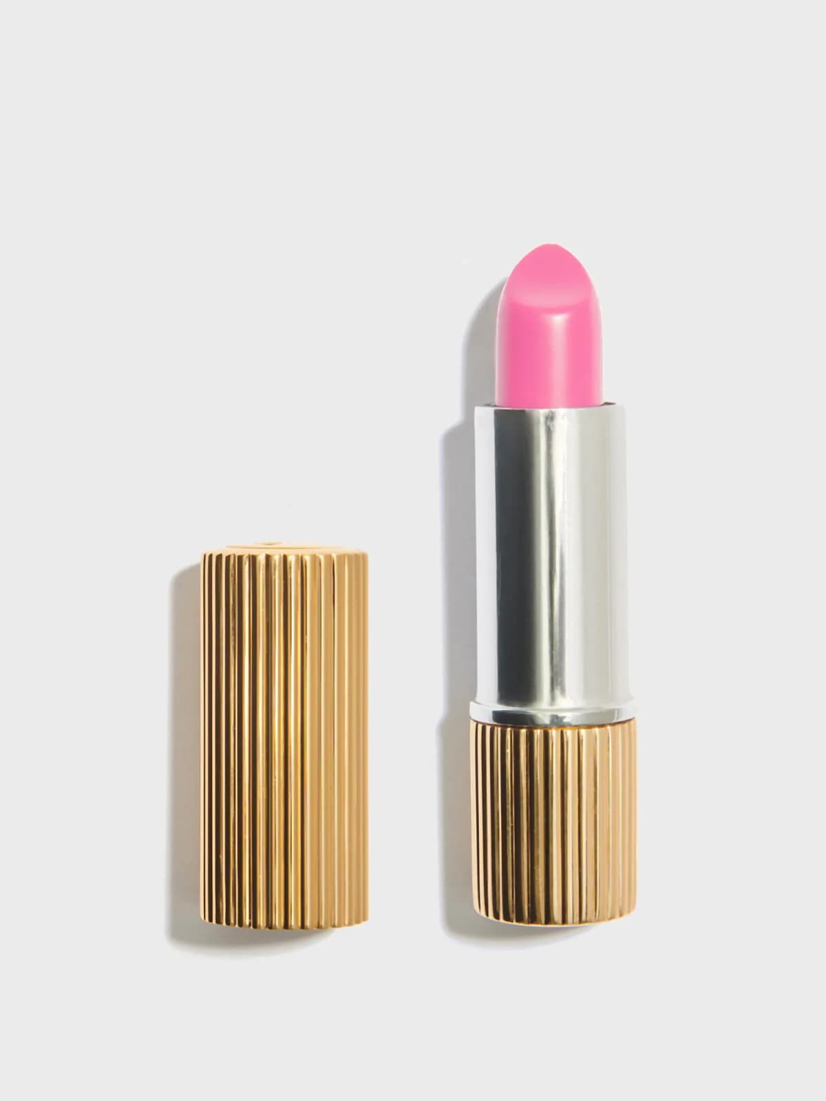 Le Baume Bonbon in Rose Bonbon, a candy-pink bullet in a silver and gold ribbed case beside its fluted gold cap