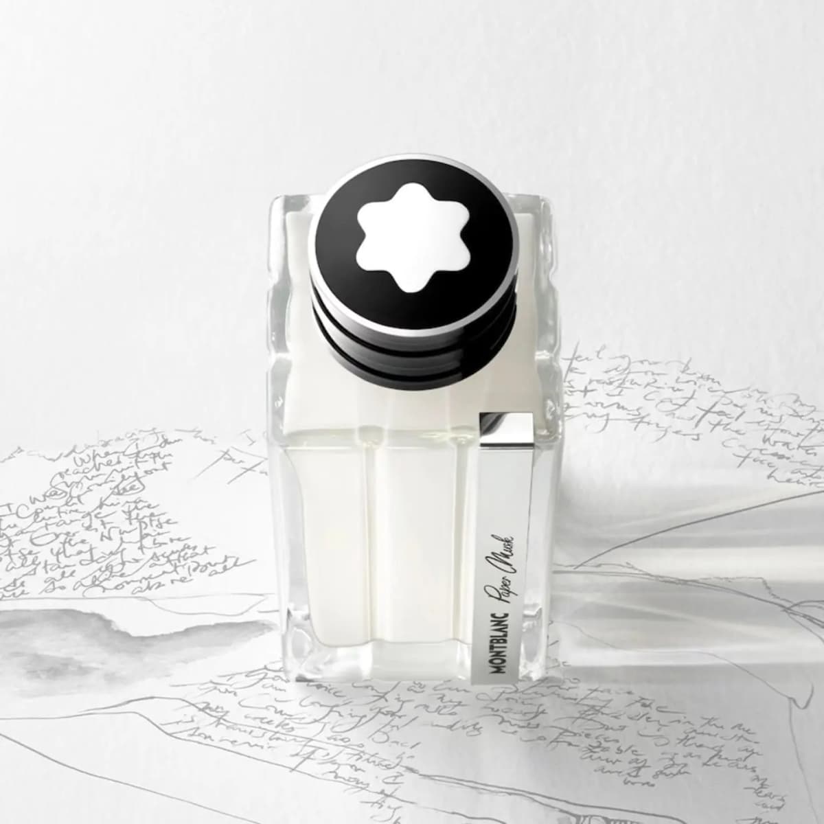 Top view of Paper Musk bottle showing the white Montblanc star cap on handwritten-script paper