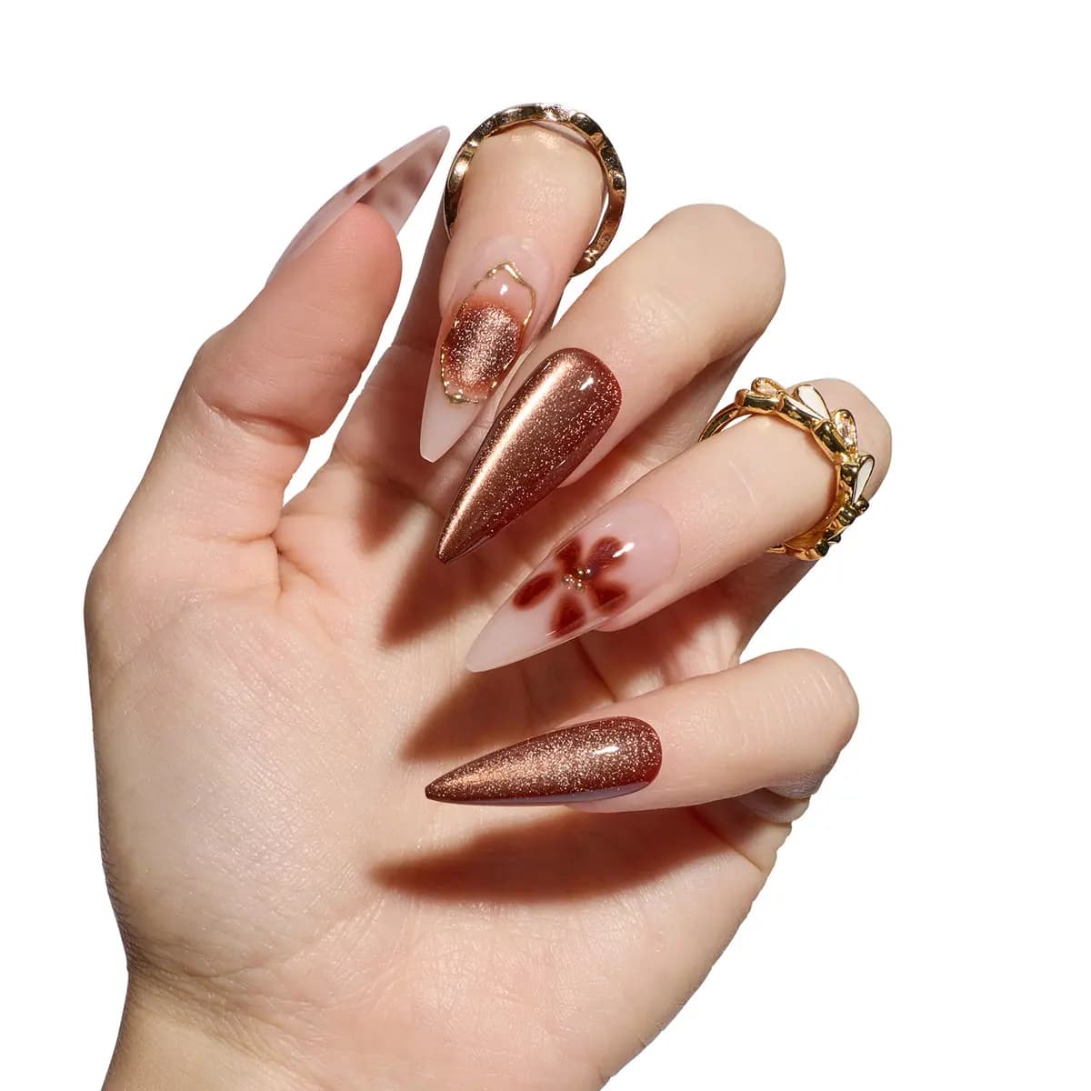 Hand wearing Mocha Mirage stilettos in shimmering copper cat-eye, nude with brown blurred flower, and gold-outlined accent.