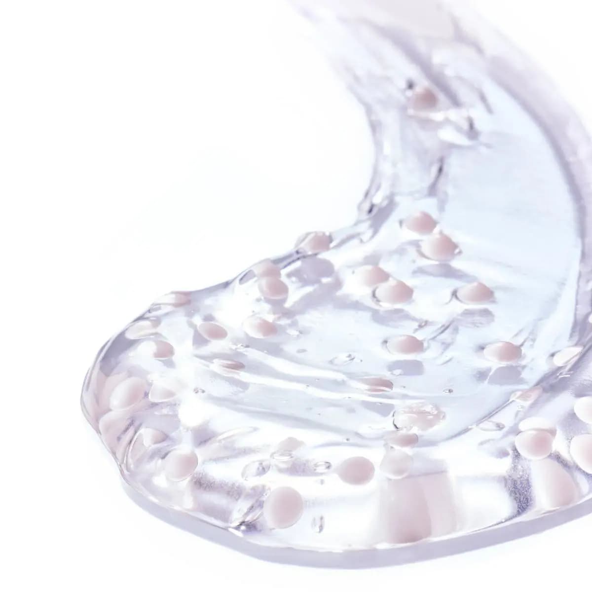 Clear gel swatch dotted with soft pink beads on a white surface