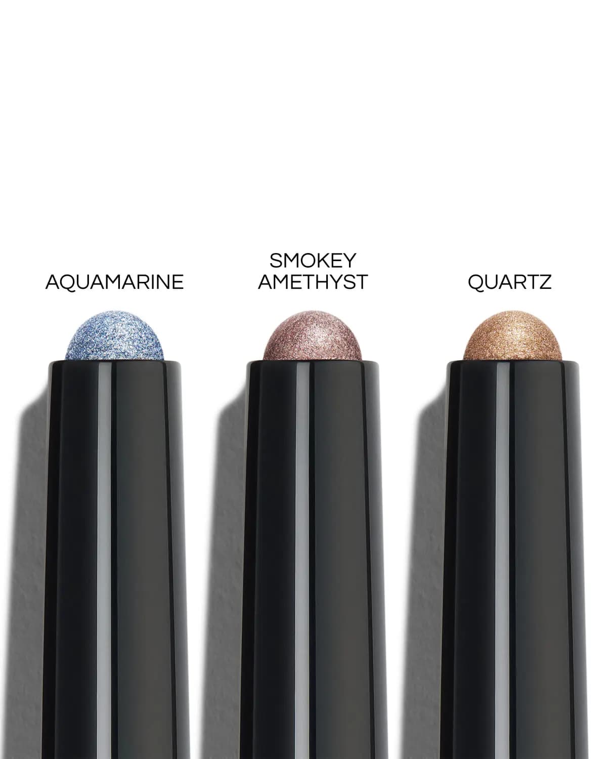 Close-up of three shadow stick tips labelled Aquamarine, Smokey Amethyst and Quartz, showing sparkling textures