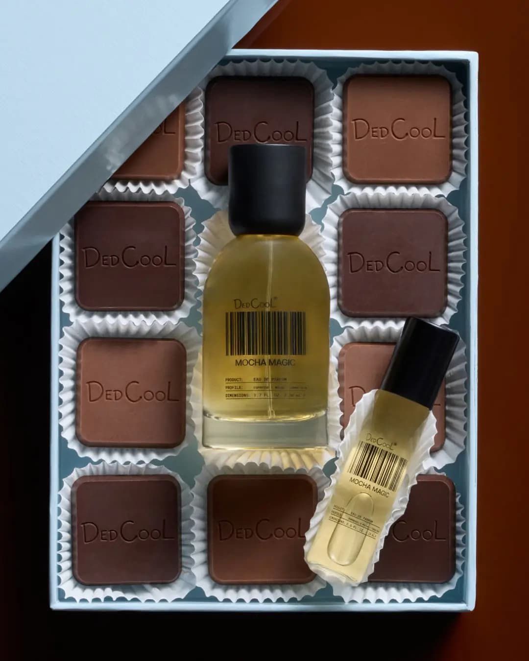 DedCool Mocha Magic perfume bottle nestled in a light blue box among branded chocolate squares in white paper cups