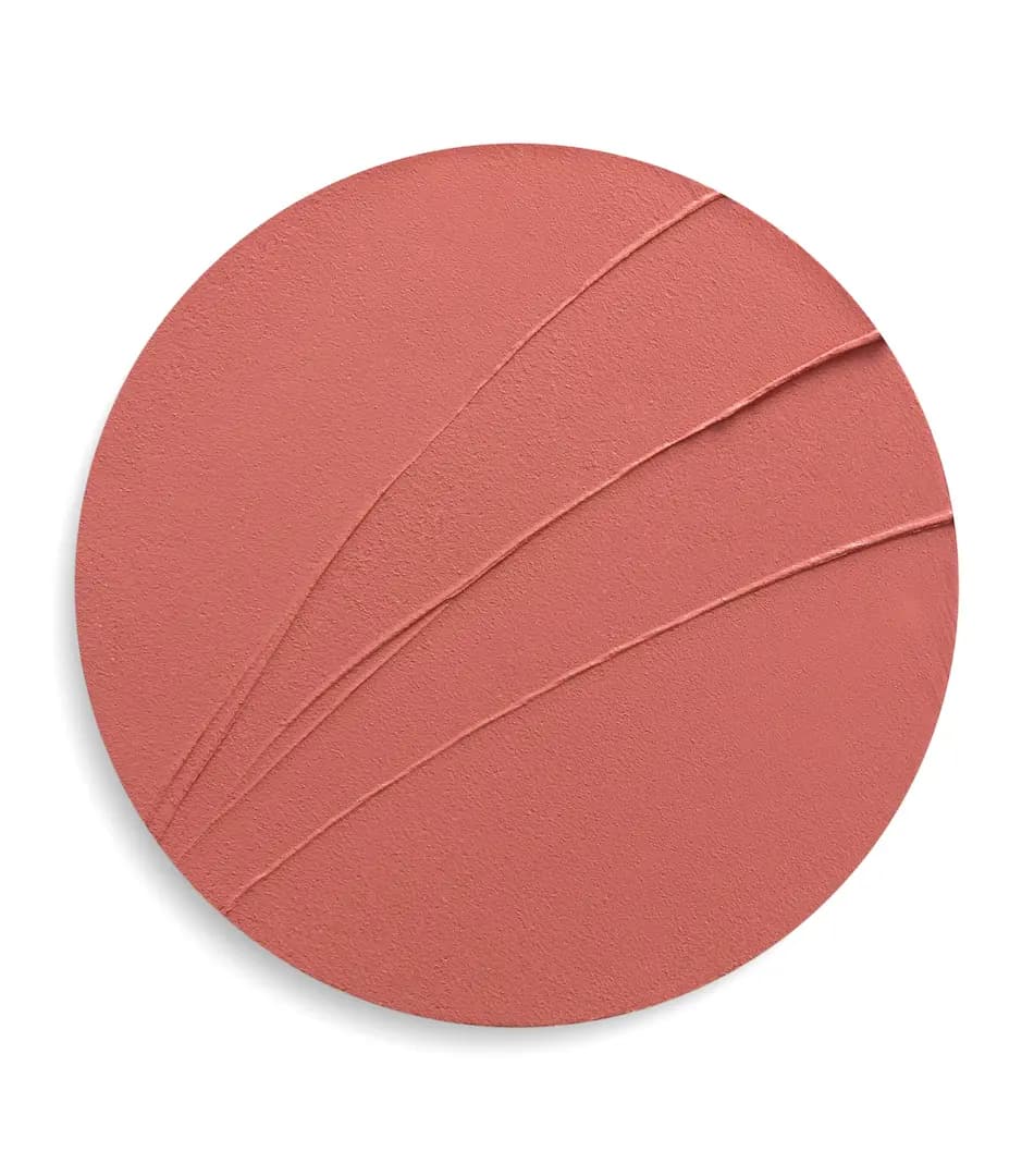 Round swatch of matte coral-rose lipstick with smooth swept lines across the creamy textured surface