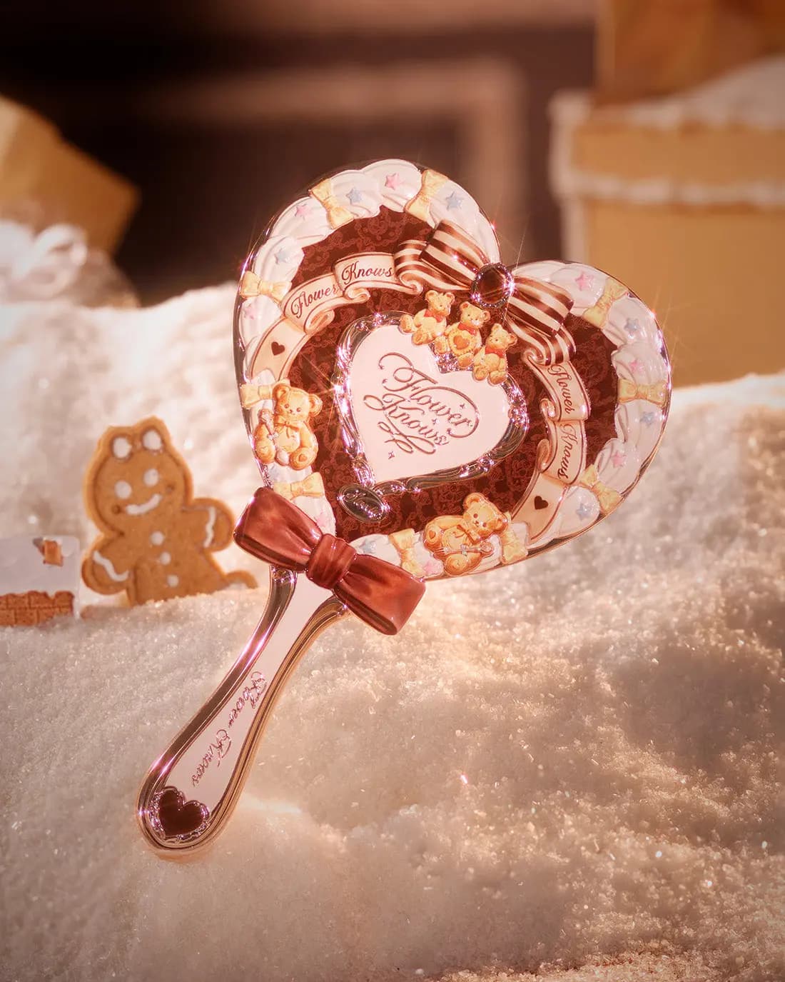 Heart-shaped Christmas Hand Mirror in Cocoa Brown with cream piping, teddy bears and a red bow, standing in snow