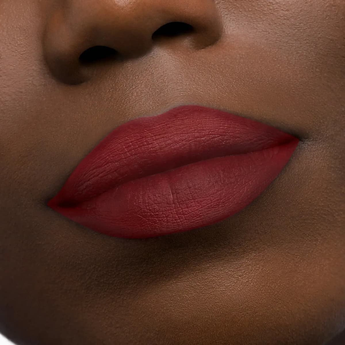 Deep red matte lipstick applied to lips on deep skin