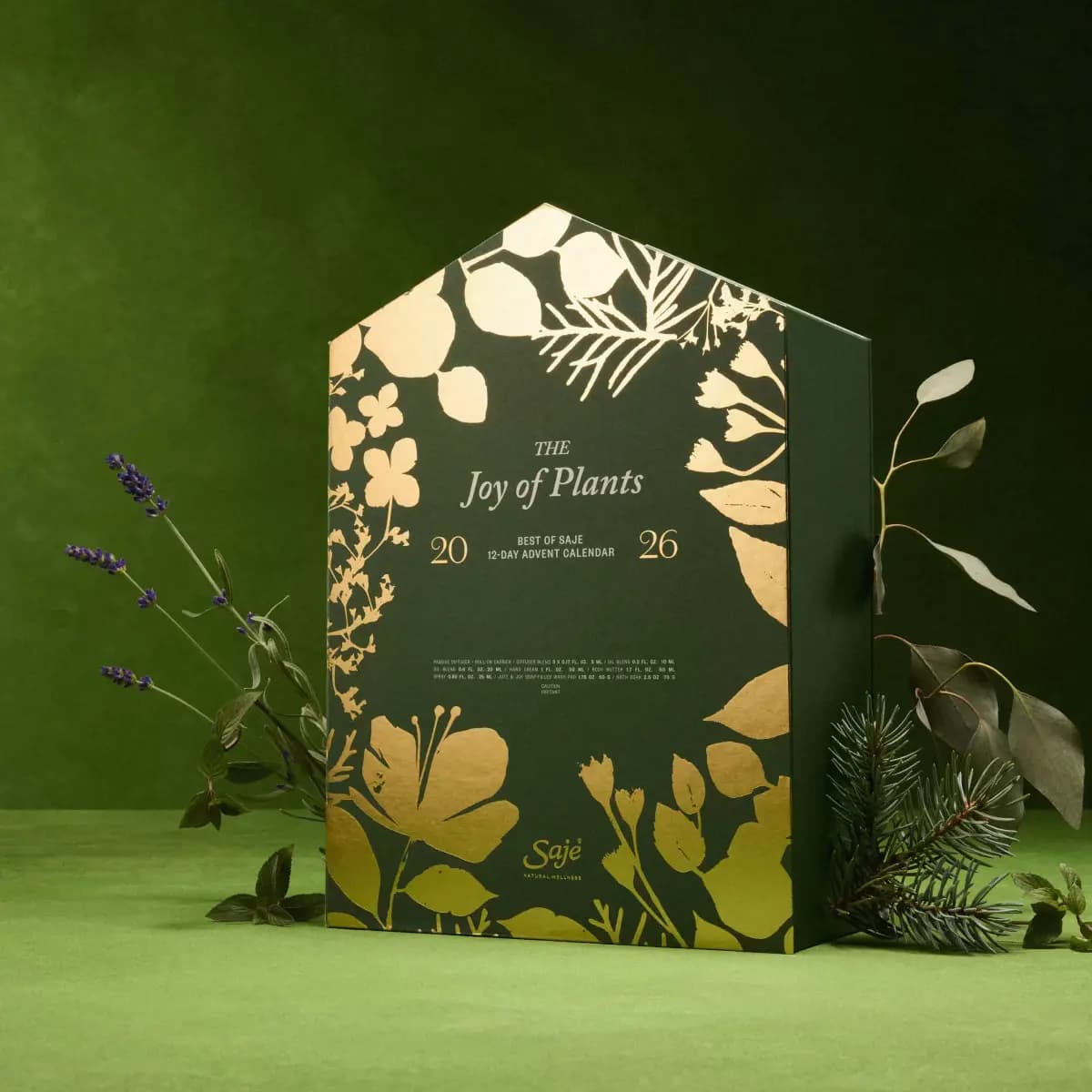 Green house-shaped Joy of Plants 2026 calendar with gold botanical foil, styled with lavender, eucalyptus and pine sprigs
