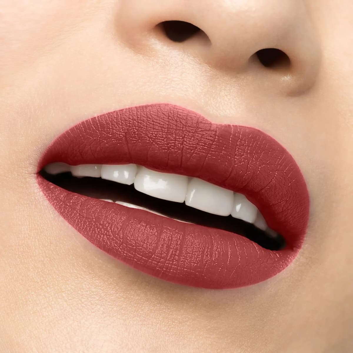 Smiling lips wearing a muted red matte shade on fair skin