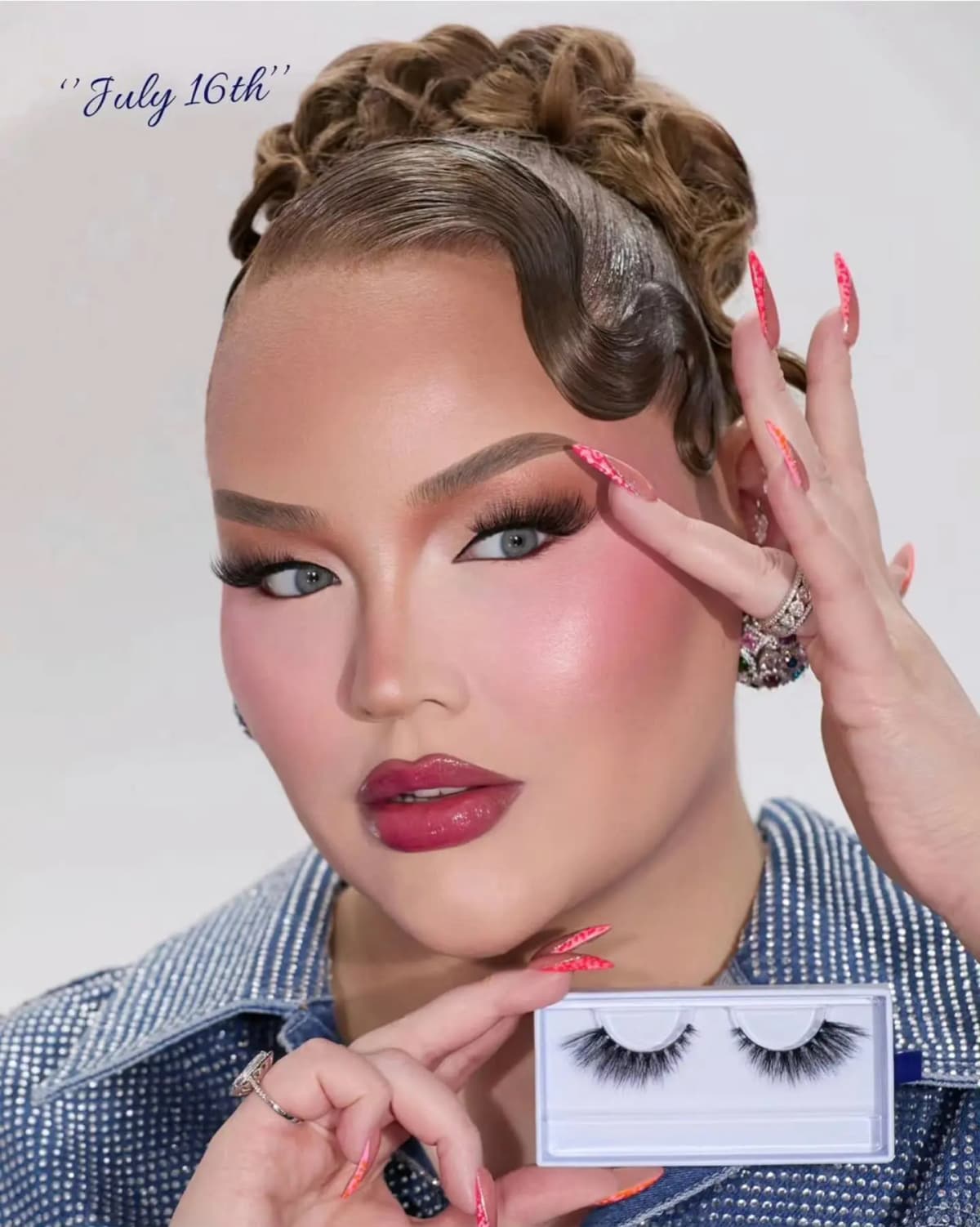 NikkieTutorials holding a pair of false lashes in a white case beside her face, labeled 'July 16th' in navy script.