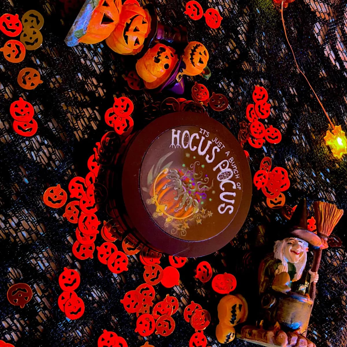 Touch of Glam Beauty Hocus Pocus pumpkin highlighter compact with witch lid art among pumpkin confetti and figurines