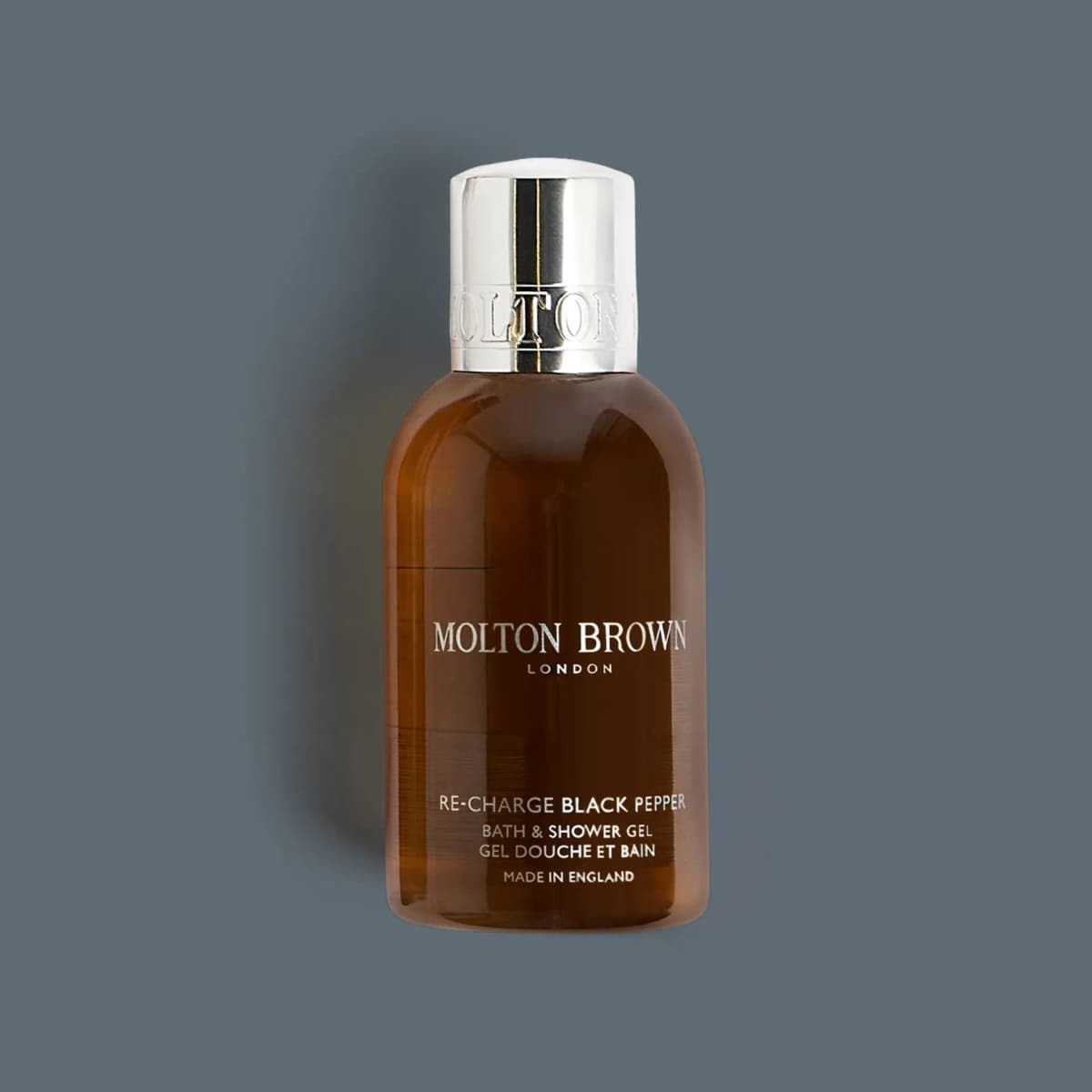 Amber Molton Brown Re-Charge Black Pepper Bath & Shower Gel bottle with shiny silver cap on slate grey