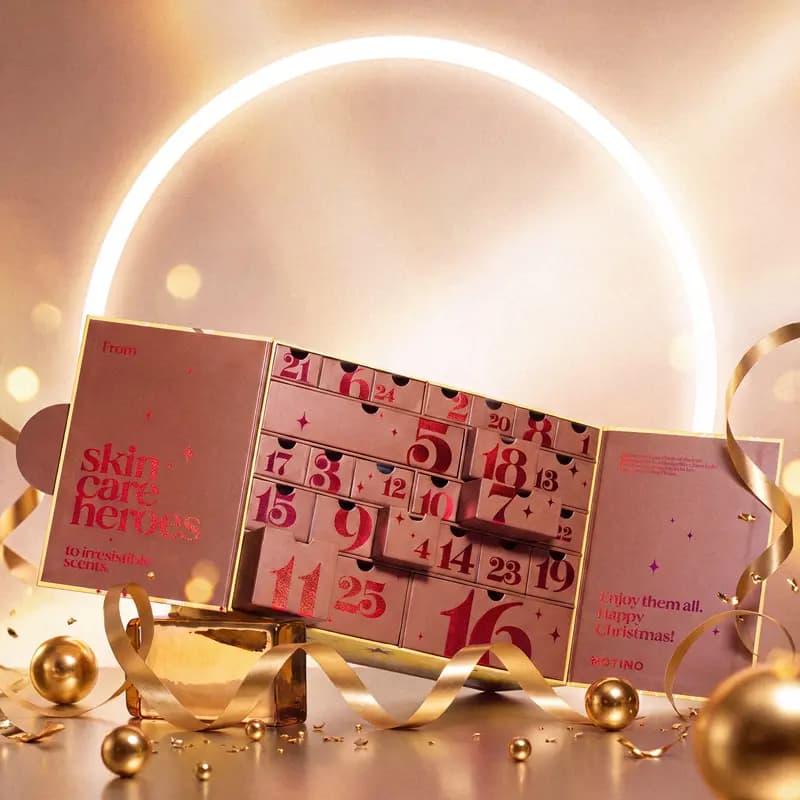Open Exclusive calendar revealing numbered pink drawers with red foil text reading skin care heroes and Happy Christmas