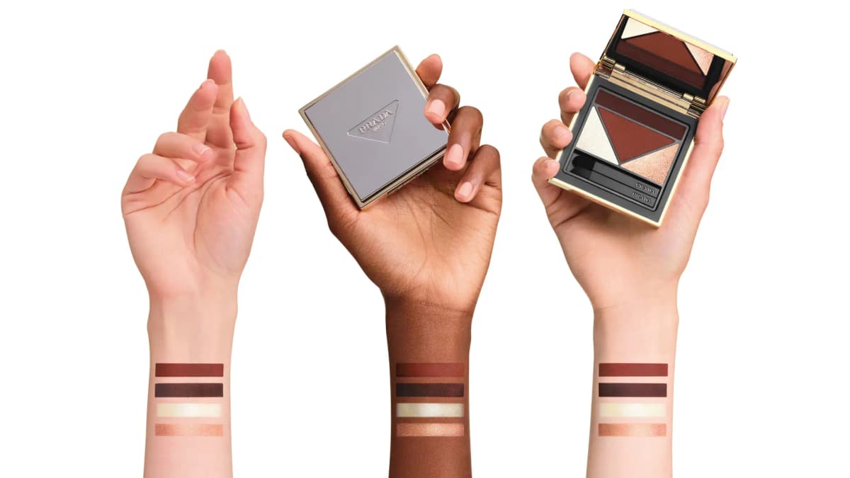 Three arms with palette shades swatched on wrists, one hand holding the silver compact, another the open palette