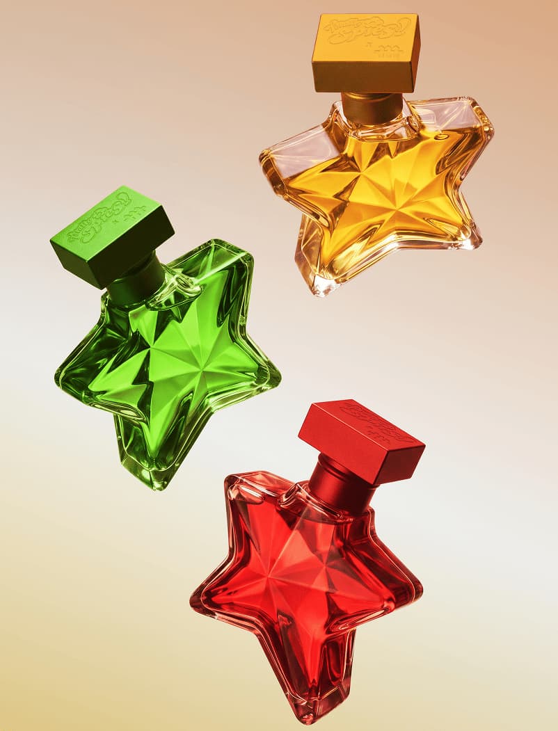 Three star-shaped perfume bottles in green, yellow and red floating against a warm gradient background.
