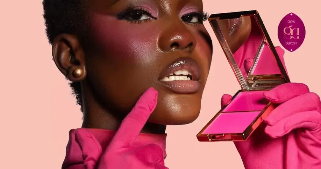 Model with short natural hair and bold pink blush holds an open hot-pink compact in pink gloves