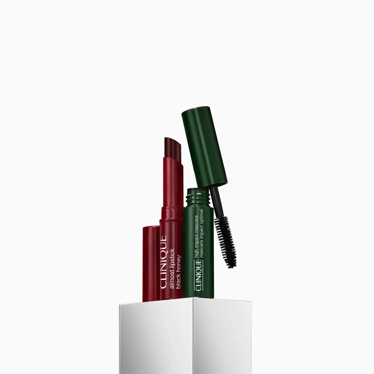 Almost Lipstick in Black Honey next to a mini green High Impact Mascara with its wand out