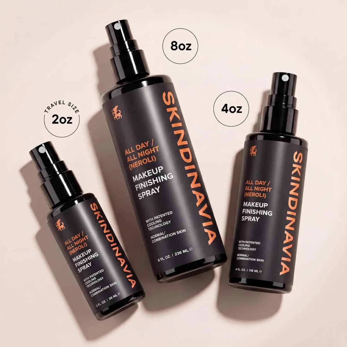 All Day / All Night Neroli spray in 2 oz, 8 oz and 4 oz black bottles laid flat on a blush backdrop