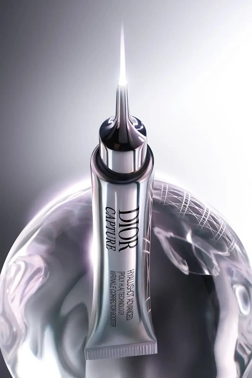 Silver tube rising from a translucent sphere etched with fine lines, its applicator tip glowing with light