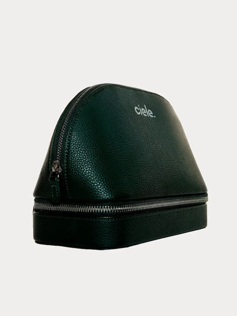 Empty dark green pebbled ciele cosmetic case with dome top and zippered lower compartment, side view