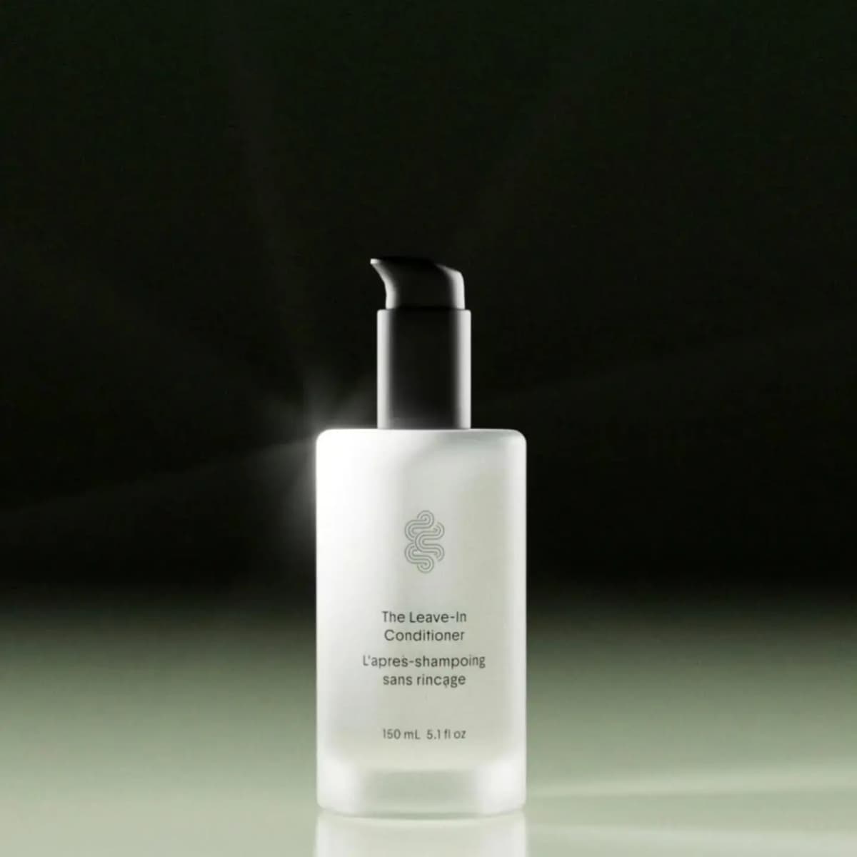 Frosted glass Crown Affair The Leave-In Conditioner pump bottle, 150 mL, lit against a dark background