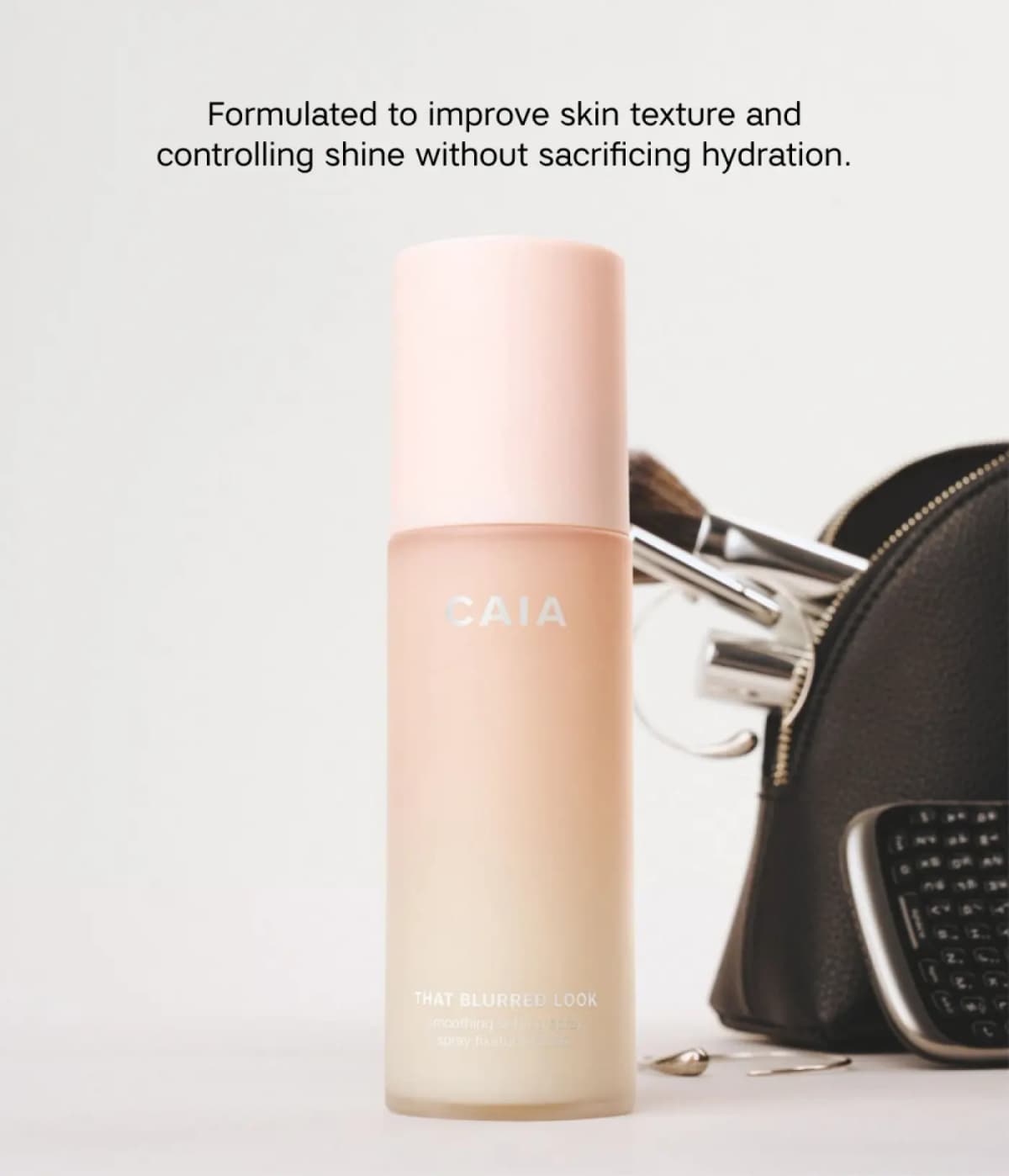 CAIA That Blurred Look bottle beside a black makeup bag with brushes, noting texture-improving, shine-controlling formula