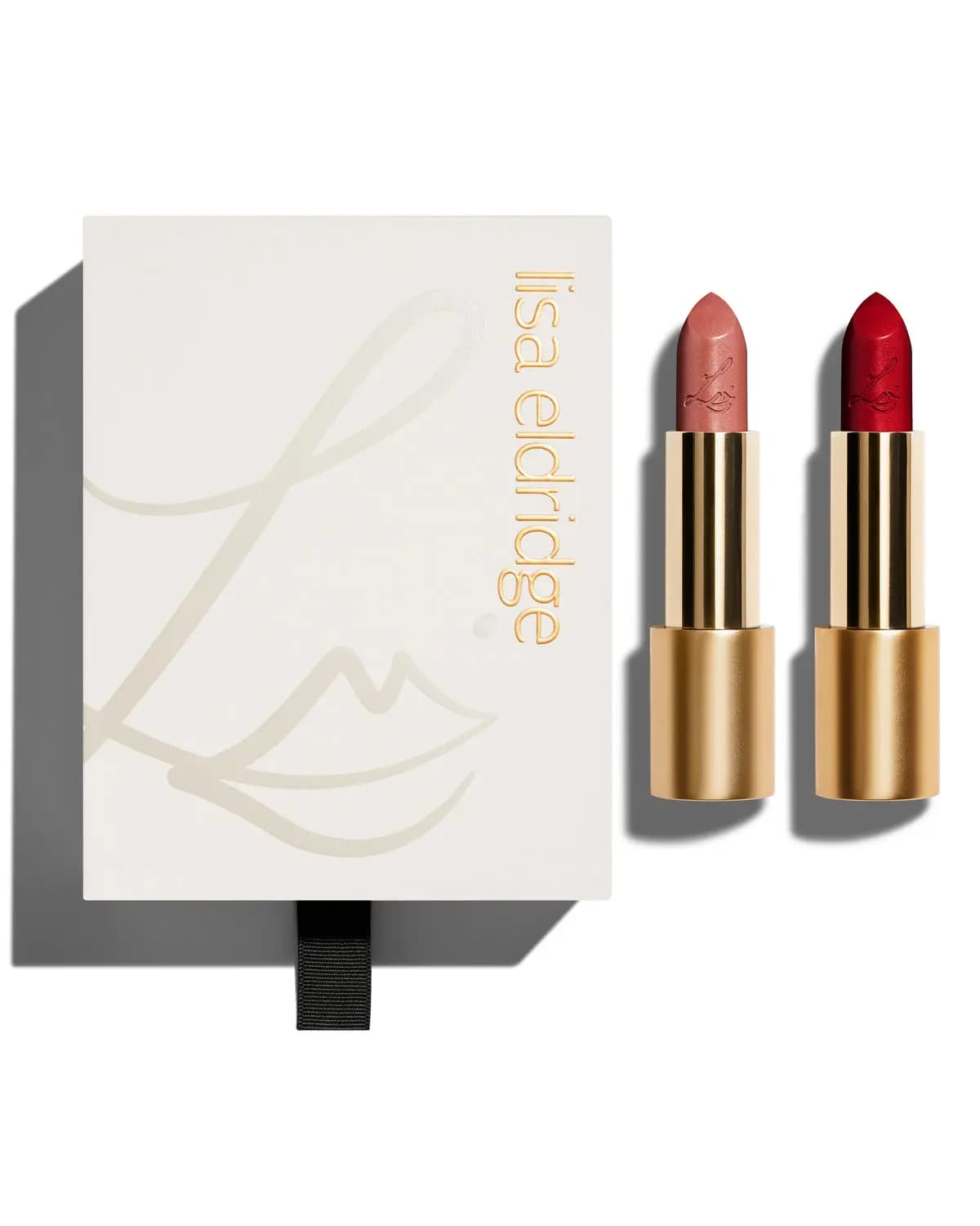 Ivory Lisa Eldridge gift box with a pull tab beside two gold-cased lipsticks in a pink nude and a deep red