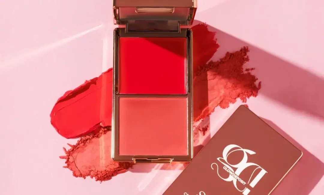Open compact with bright red cream and coral powder blush over matching swatches, beside a rose-brown Glow Deposit box