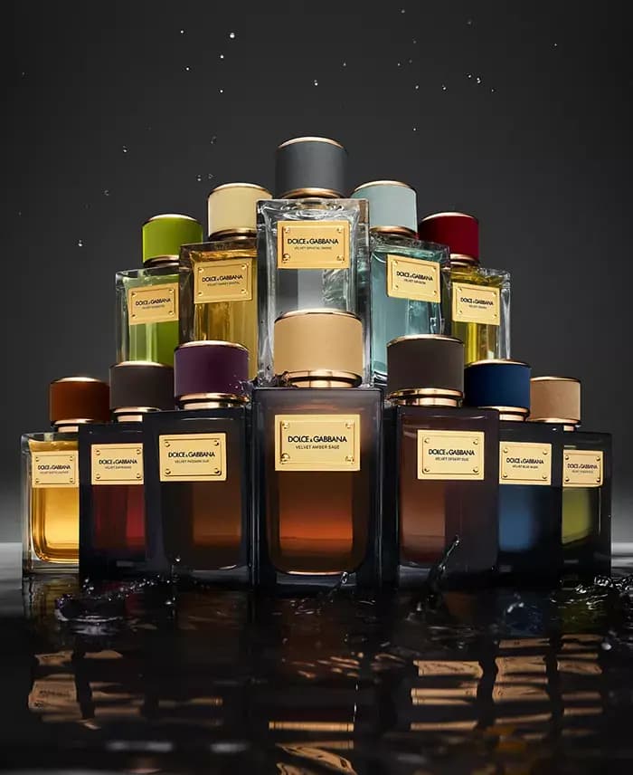Velvet Collection bottles with coloured velvet caps stacked in a pyramid above splashing dark water