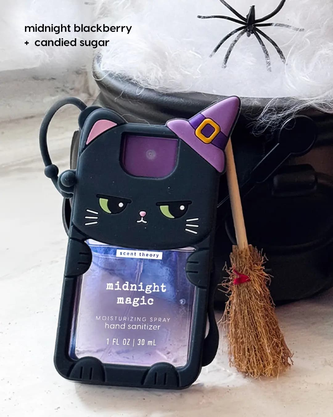 Midnight Magic hand sanitizer in a black cat holder with purple witch hat, beside a mini broom and cauldron