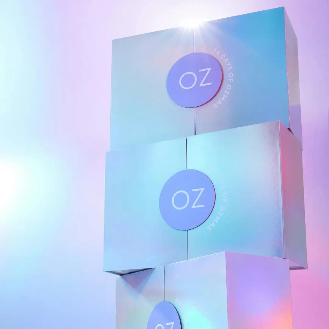 Three holographic calendar boxes stacked against a soft pink and blue gradient backdrop