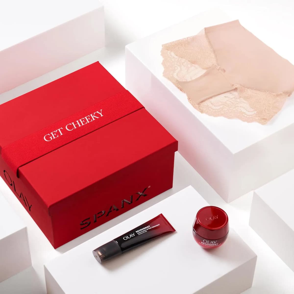 Closed Get Cheeky red box on white blocks with a Soft Nude lace hi-hipster and two OLAY Regenerist products
