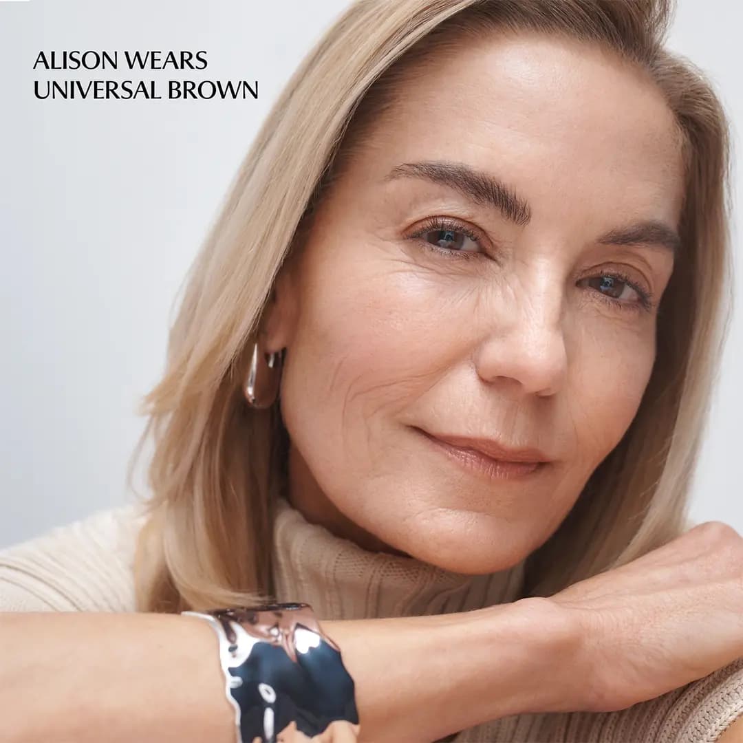 Blonde model Alison in a beige turtleneck and silver cuff wears Universal Brown on softly defined brows.