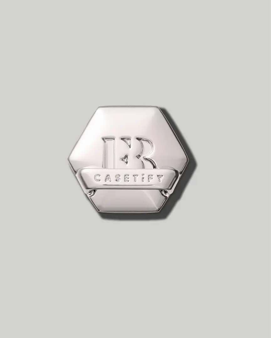Silver hexagon charm embossed with the FB monogram and a CASETiFY banner