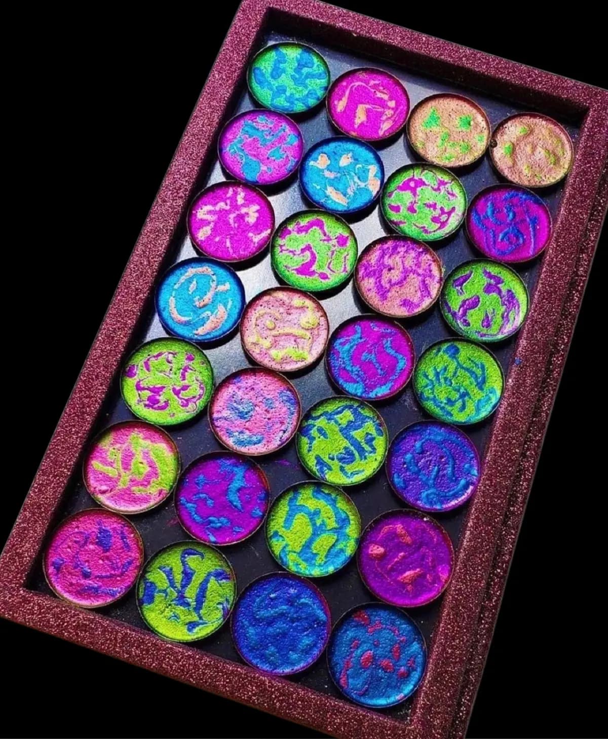 Glitter-edged palette of 28 marbled eyeshadows in neon green, magenta, blue and purple swirls