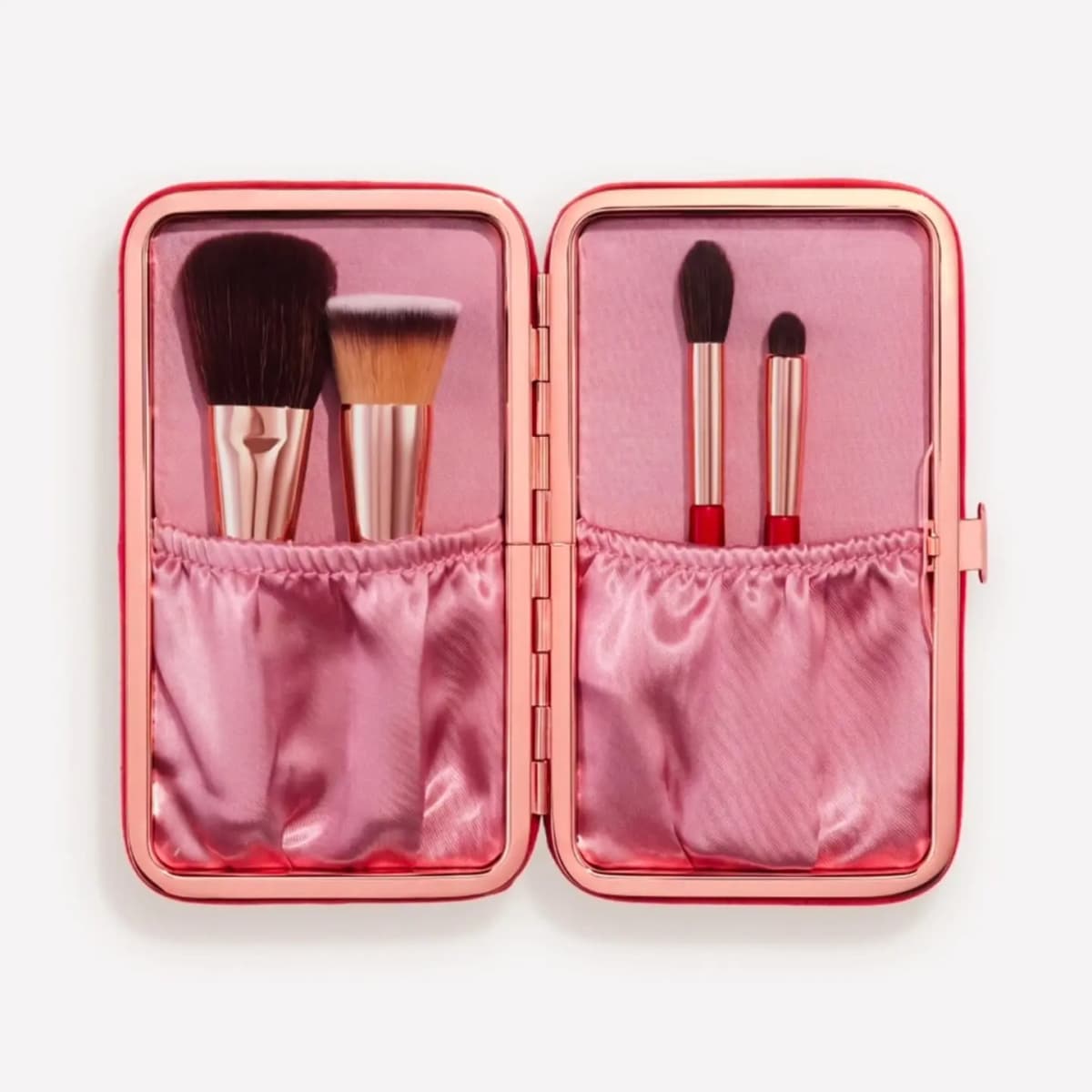 Open red-velvet case with pink satin pockets holding four makeup brushes, two with red handles