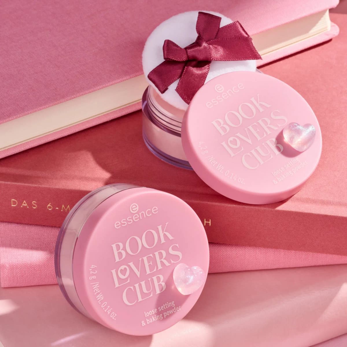Two pink jars of loose setting and baking powder with glitter heart lids on red and pink books