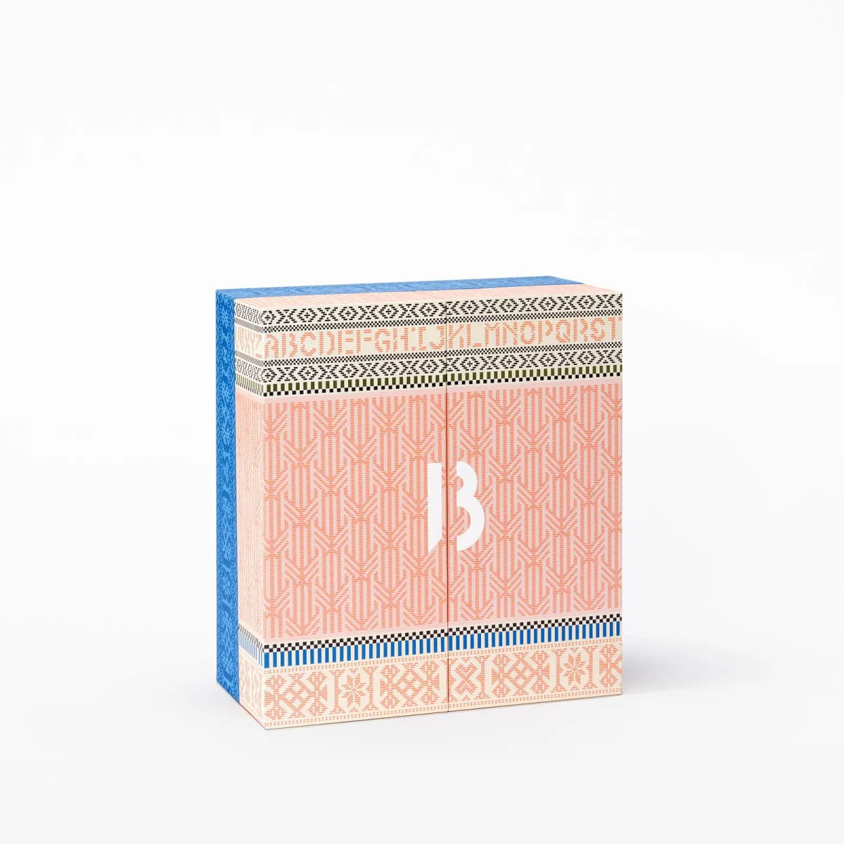 Closed square Byredo advent calendar box with peach-pink knit-effect pattern, alphabet border, white B logo and blue spine.