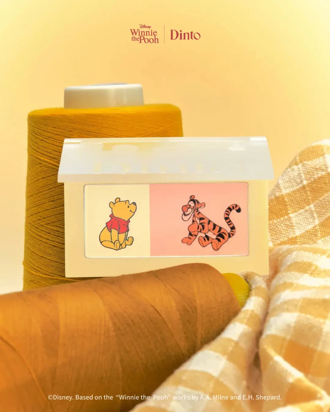 Dual blusher with yellow Pooh pan and peach Tigger pan, set against yellow thread spools and checked fabric