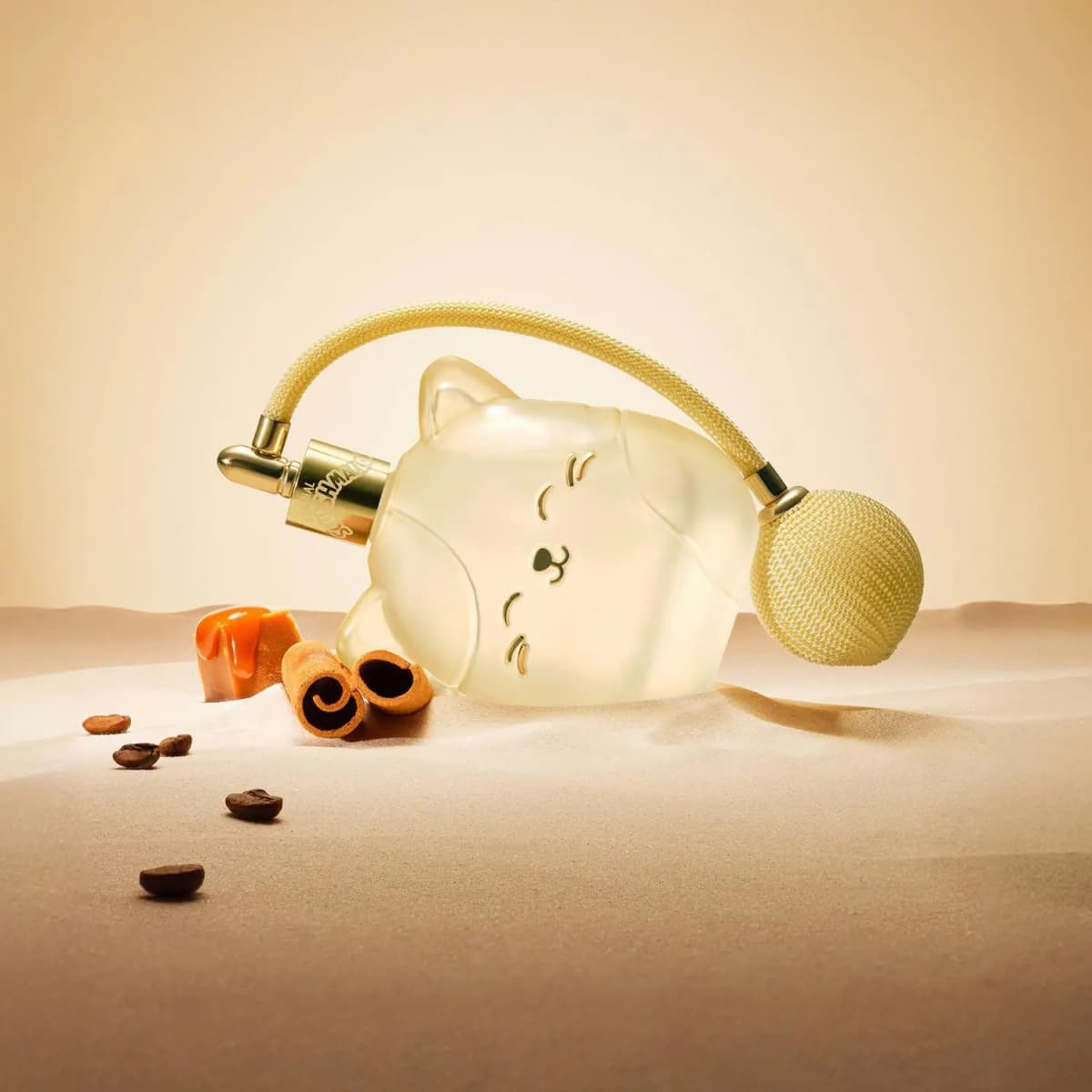 Cat perfume bottle lying in sand with caramel, cinnamon sticks and coffee beans on a warm beige backdrop