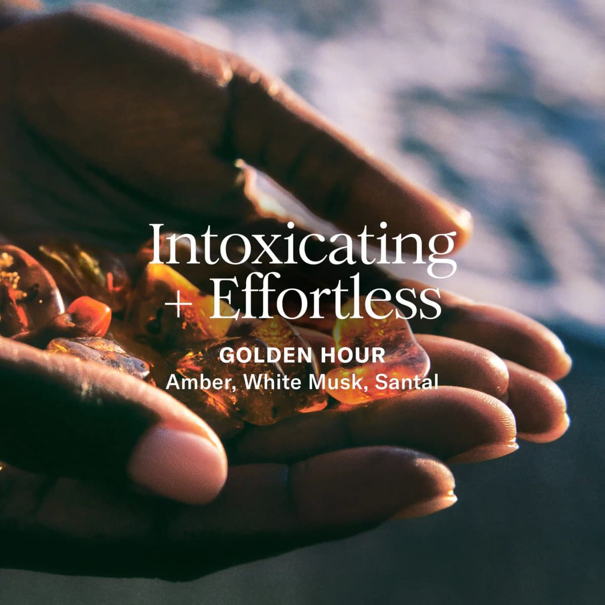 Hands cradling amber stones in sunlight with text Intoxicating + Effortless, Golden Hour, amber, white musk, santal.