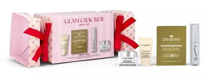 Glam Cracker Travel Set in a pink cracker-shaped box with red ribbons, beside Lancôme, MAC, Origins and Tarte minis