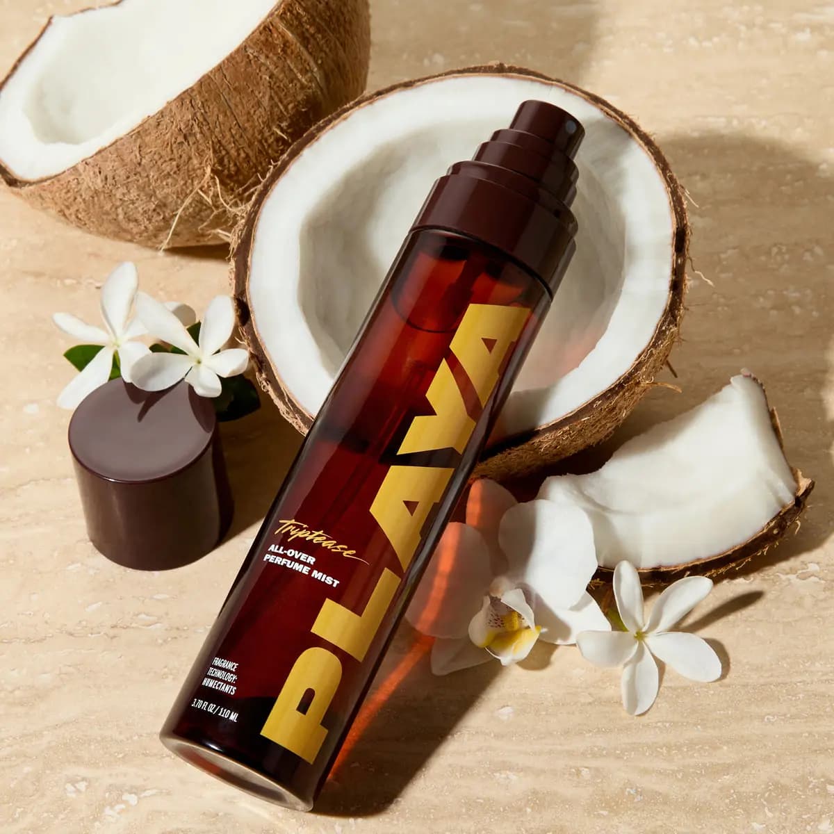 Uncapped mist bottle lying on travertine beside coconut halves, white orchid and jasmine flowers, with its cap nearby