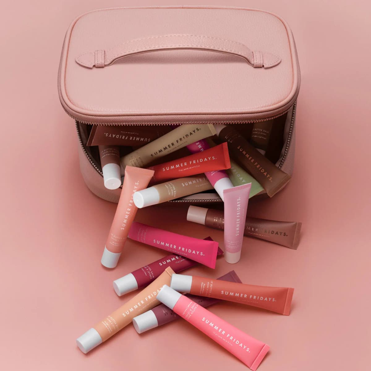 Top-down view of the open pink vanity case with Lip Butter Balm tubes spilling out onto a pink surface