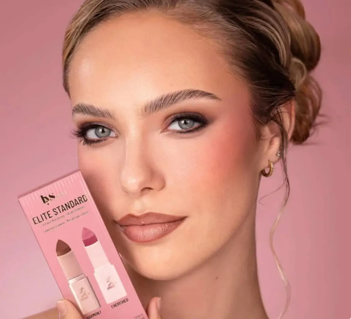 Model with soft bronzed cheeks and smoky eyes holds the Elite Standard Harmony and Cherished set up to the face