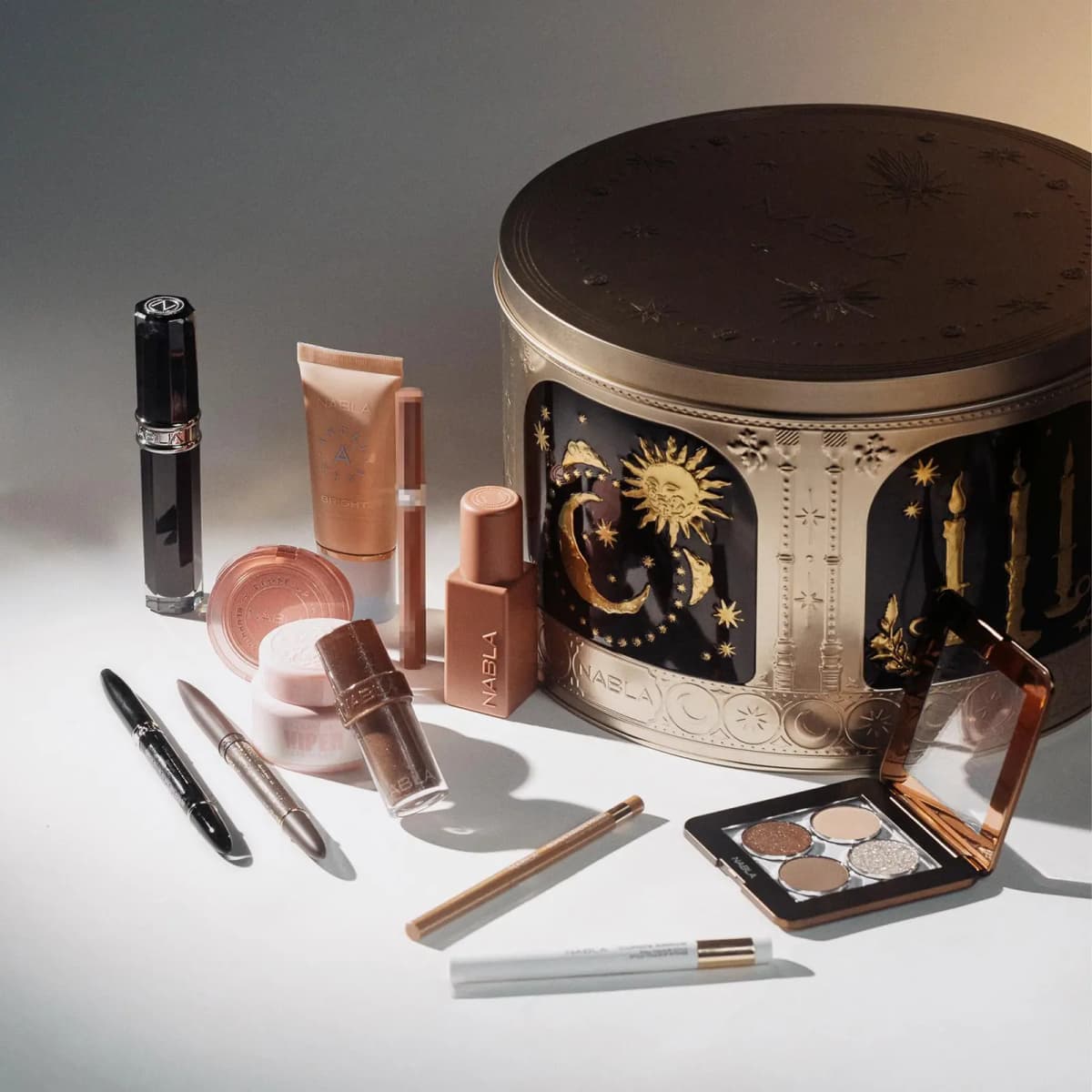 Calendar products in nude and brown tones beside the closed gold tin, with an open quad palette and liners