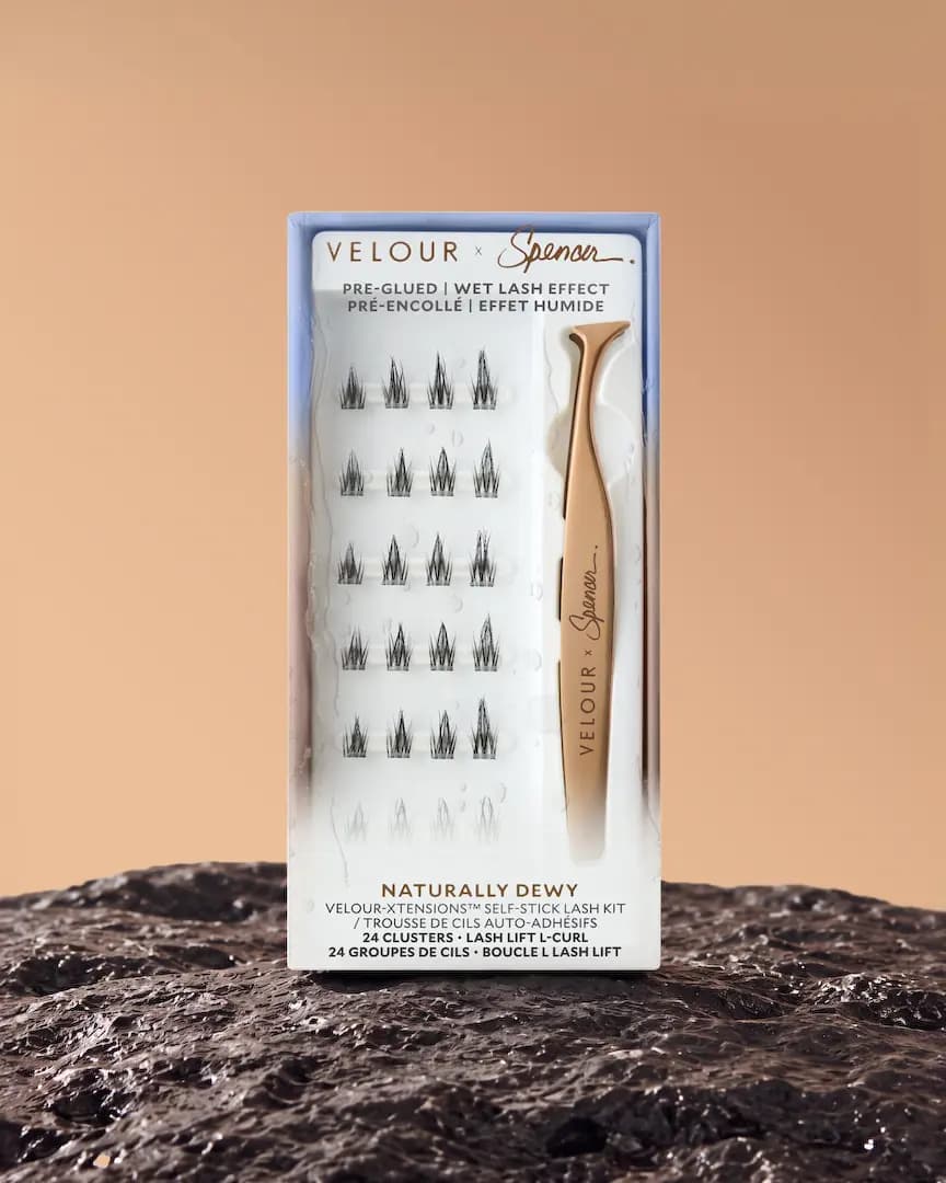 Naturally Dewy kit in a blue-to-white box with 24 lash clusters and rose-gold tweezers, set on a dark rock