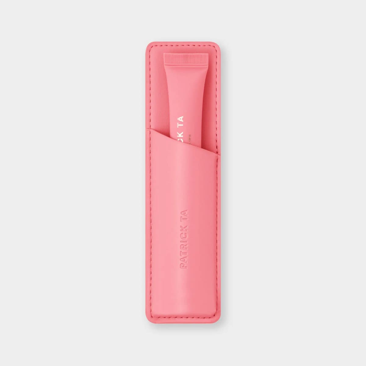 Bright pink leather lip sleeve with debossed logo holding a matching pink lip balm tube