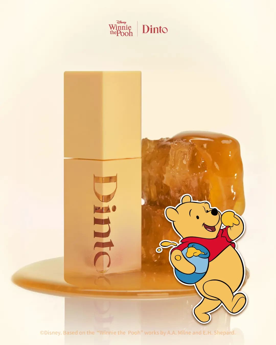 Yellow square Dinto lip tint bottle standing in a pool of honey beside honeycomb and a Pooh holding a honey pot