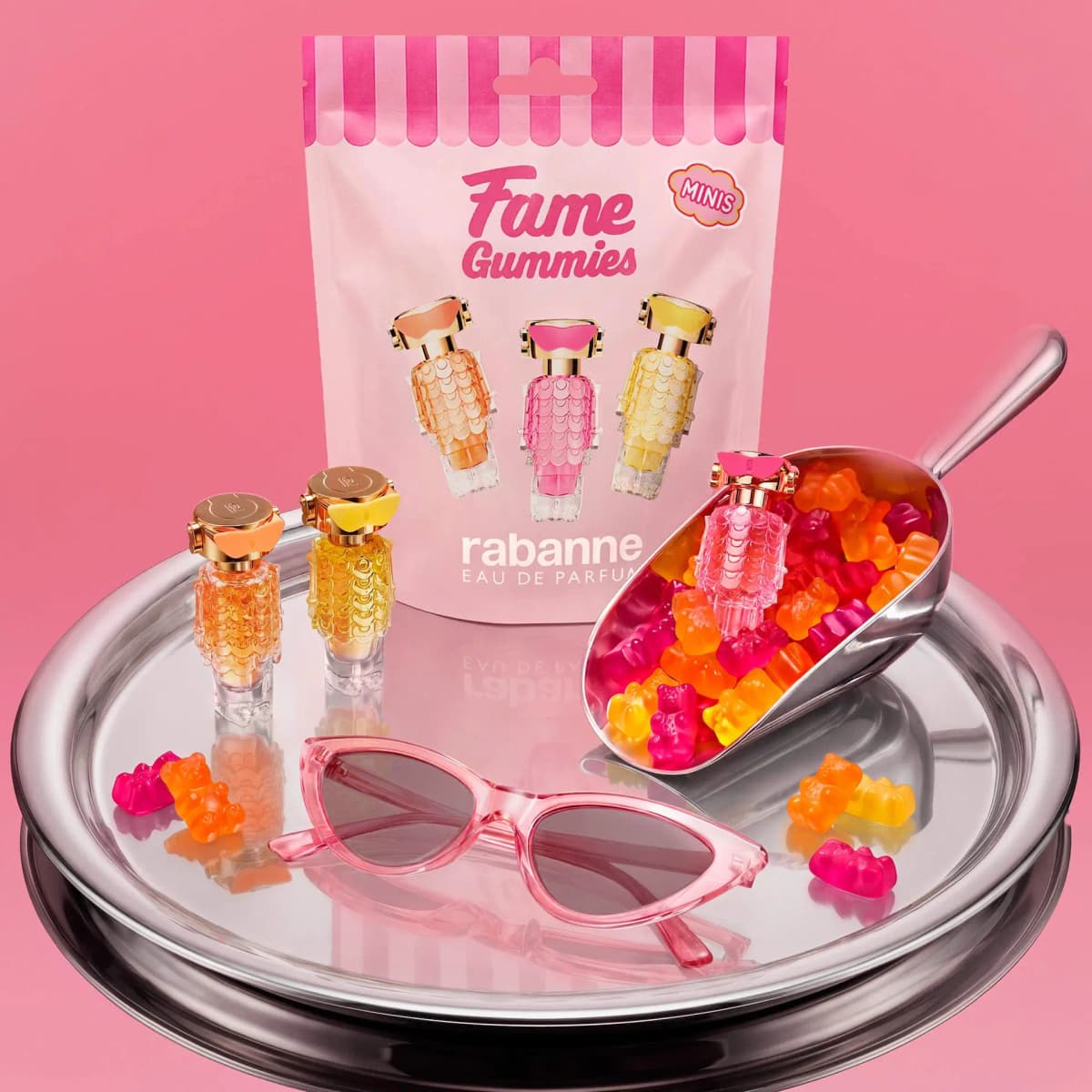 Rabanne Fame Gummies Mini Trio Perfume Gift Set pouch on a silver tray with mini bottles, gummy bears and pink sunglasses