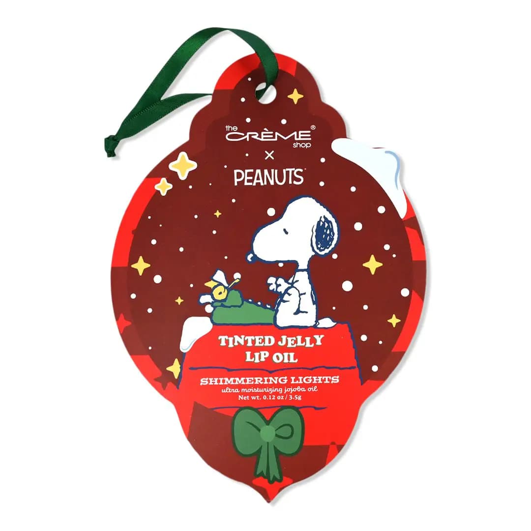Shimmering Lights Tinted Jelly Lip Oil on a red ornament card showing Snoopy at a typewriter, with green ribbon.