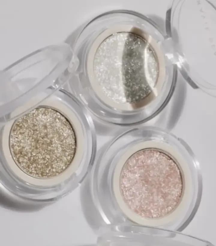 Ravie Beauty Softlight Glistening Eye Topper in Soft Pearl, Soft Gold and Soft Pink, open in clear compacts on white